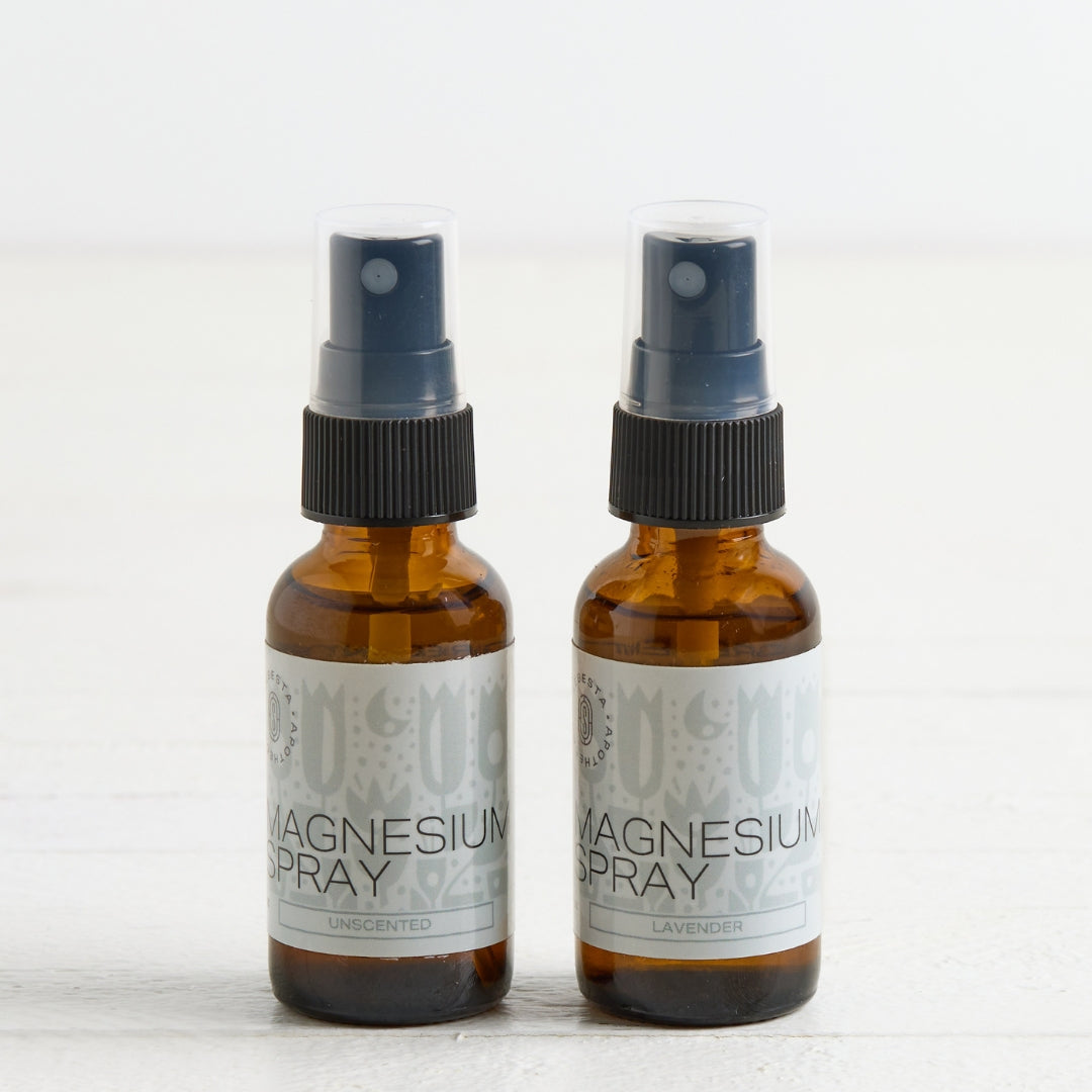 Two amber glass spray bottles labeled Magnesium Spray, standing side by side on a light surface against a white background.