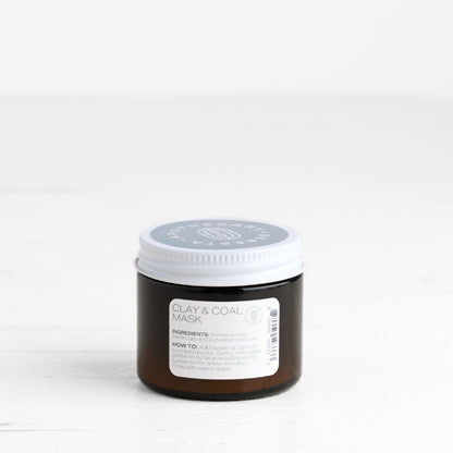 Jar of clay and coal mask on a white background