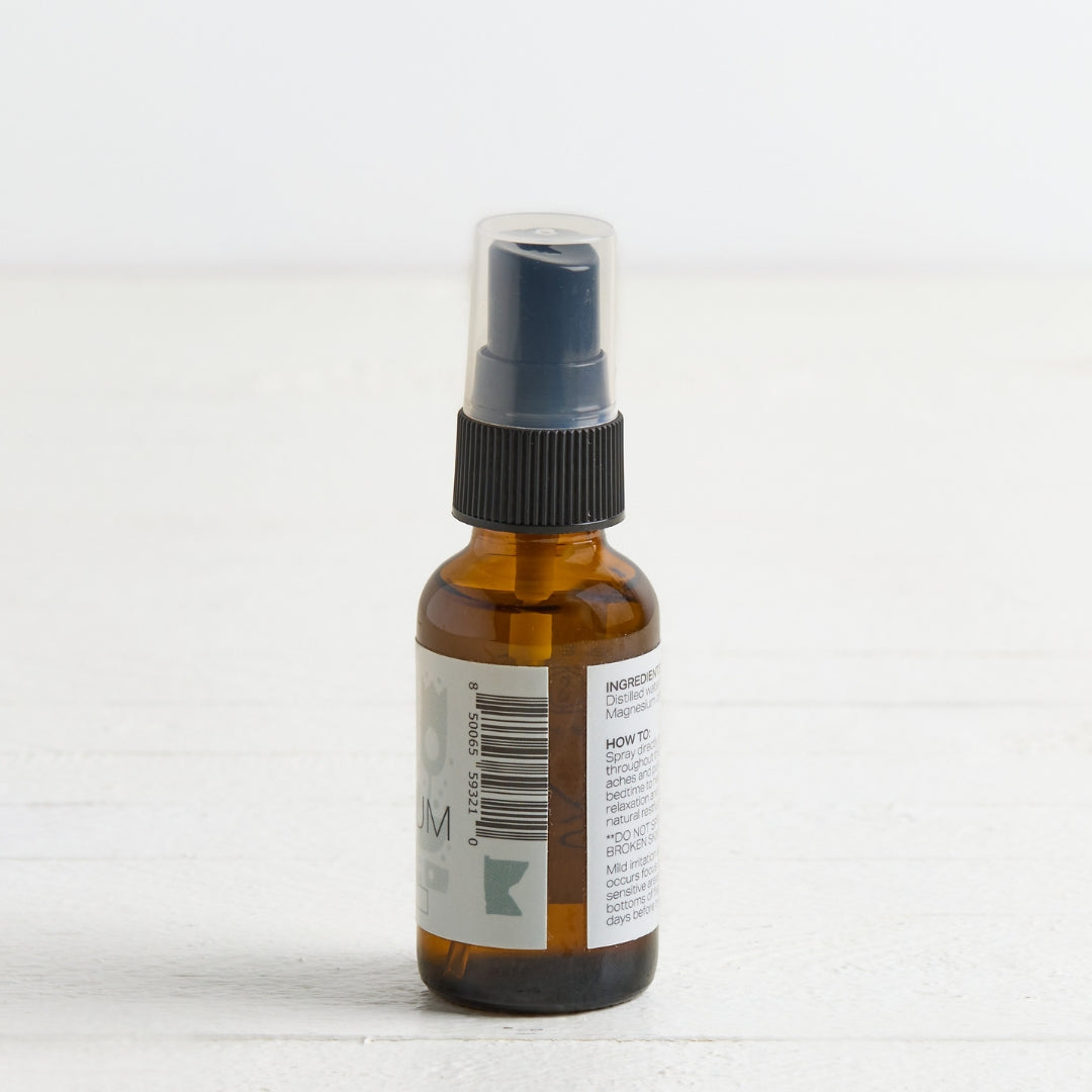 An amber glass spray bottle with a black spray nozzle and a clear protective cap, shown from the back with a white label on a light background.