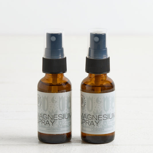 Two amber glass spray bottles labeled Magnesium Spray, standing side by side on a light surface against a white background.