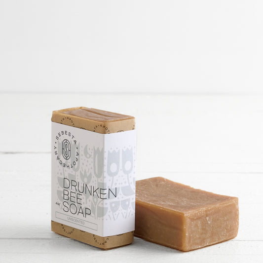 2 bars of Drunken Bee Soap with Sebesta Apothecary Branding on a white background, one Tipped on side
