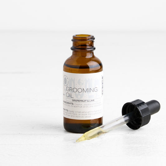 Brown glass bottle with dropper labeled 'Grooming Oil' on a white background