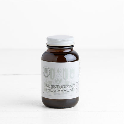 Brown bottle of moisturizing face serum with a white label on a white background